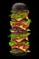 Huge appetizing black burger on black background. Ham, beef cutlet, cheese, vegetables and greens. Cooking and fast food