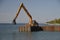 Huge backhoe drives pilings into the water