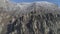 Huge and bizarre shaped rock formation on the mountain hillside with shrubs and small trees. Shot. Aerial view.