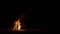 A huge bonfire on sand. Lots of sparks. Silhouette of man with mobile device.