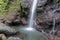 Huge boulders and pieces of rock falling into a pond under a waterfall. Pure water from a mountain river flows down a rock. Moss