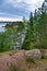 Huge boulders stones covered with moss and pine forest near beatiful fresh blue lake, Park Mon Repos, Vyborg, Russia