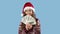 Huge Christmas discount. Happy young woman in Santa hat and woolen sweater holding money on blue background