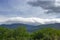 Huge clouds over mountains with green trees forehead. Nature and element concept. Storm background.