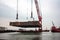 huge crane lifting massive steel plate to new ship