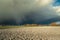 Huge dark hail cloud over the plowed field, view on a spring day