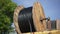 Huge electrical wire roll outdoors with blue summer sky at background. Industrial equipment spinning in sunshine at