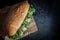 Huge fresh crispy baguette sandwich with meat, prosciutto, cheese, lettuce salad and vegetables