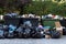 Huge garbage piles next to the dumpster after city fair. Stacks of litter bags overflow trash cans after festival in a city