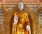 Huge gold statue of standing Buddha in buddhist temple