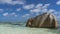 A huge granite boulder with folded slopes rises in the ocean.