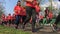 Huge group of women in orange t-shirts with numbers running marathon in the park in spring. Running women legs.