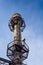 Huge industrial smokestack ringed with walkways and ladders before a brilliant blue sky