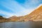 Huge lake in the mountains with a little house on the dock. Nice blue sky with some clouds. Shot in Romania, Transfagarasan