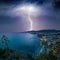 Huge lightning from dark stormy sky strikes coastal city