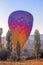 Huge multi-colored balloon landed on the ground in Cappadocia against the sun after flying at dawn, on the goreme hills