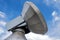 Huge parabolic antenna against a blue sky with white clouds