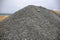 Huge pile of grey gravel on coast. Construction site material. Big gravel heap outdoor. Construction supply closeup.