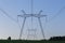 Huge power line towers on field at summer evening