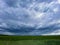 Huge purple storm clouds over a green field. Copy space