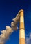 Huge red and white chimney rising high above towards a blue sky belches out v