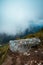 Huge rock on the ground with a background of a landscape in misty weather, vertical shot