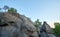 Huge rocky boulder formations high in mountains with growing trees on summer sunny day