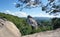 Huge rocky boulder formations high in mountains with growing trees on summer sunny day