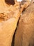 Huge sandstone rock with a crack in the middle of if. Yellow limestone cliff that have cracked apart.