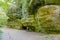 Huge sandstone rock formation, footpath, female hiking tourist sitting on a wooden bench next to her brown dog