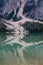 Huge scree slopes ending in water of Lake Braies, South Tyrol, Italy. Scenery reflected on calm water surface