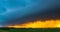 Huge shelf cloud out ahead of a cool outflow of air from a thunderstorm over cropland, time lapse, amazing sunset light