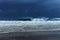 Huge shore breaking wave with distant storm