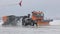 Huge snow blower clear the runway. A large orange machine removes snow