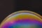 Huge soap bubble with colourful pattern against dark brown background