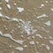 Huge sparkling snowflake on the sand in the sea foam. Concept of Winter and Christmas vacation on the beach and resort.