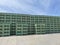 Huge stack of plastic crates of solid green color outside storage of vegetable empty containers under the sky.