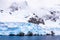 Huge steep stone rock covered with blue glacier and cloud with water in foreground, close to Argentine islands, Antarctic