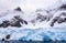 Huge steep stone rock covered with blue glacier and cloud with water in foreground, close to Argentine islands, Antarctic