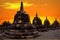 Huge stone Buddhist stupas against the background of a beautiful orange sunrise in the Borobudur Temple. Indonesia. Java island.