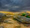 huge stones on sand under a dense dramatic cloudy sky