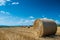 Huge straw bales near roadside at summertime, blue summer sky with white clouds
