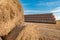 Huge straw pile of Hay roll bales on among harvested field. cattle bedding