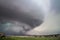 A huge supercell storm with a ground scraping wall cloud and lightning bolt