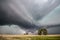 A huge supercell thunderstorm with a low wall cloud causes torrential rain and severe hail.