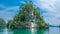 Huge Triangle Rock overgrown with Palmtrees in Hidden Bay on Gam Island near Kabui and Passage. West Papuan, Raja Ampat, Indonesia