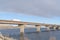 Huge trucks travelling on a massive bridge against snowy hills and cloudy sky