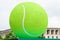 Huge vivid green tennis ball displayed outdoor near a crowded square in Bucharest, Romania