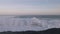 Huge waves crashing against the rocks and releasing large amounts of white foam