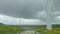 Huge wind turbine blades rotating under gray rainy sky, storm, vertical panorama